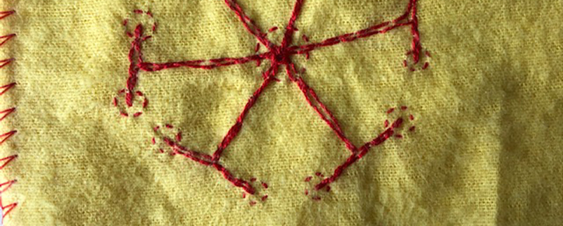 red embroidery on a yellow duster